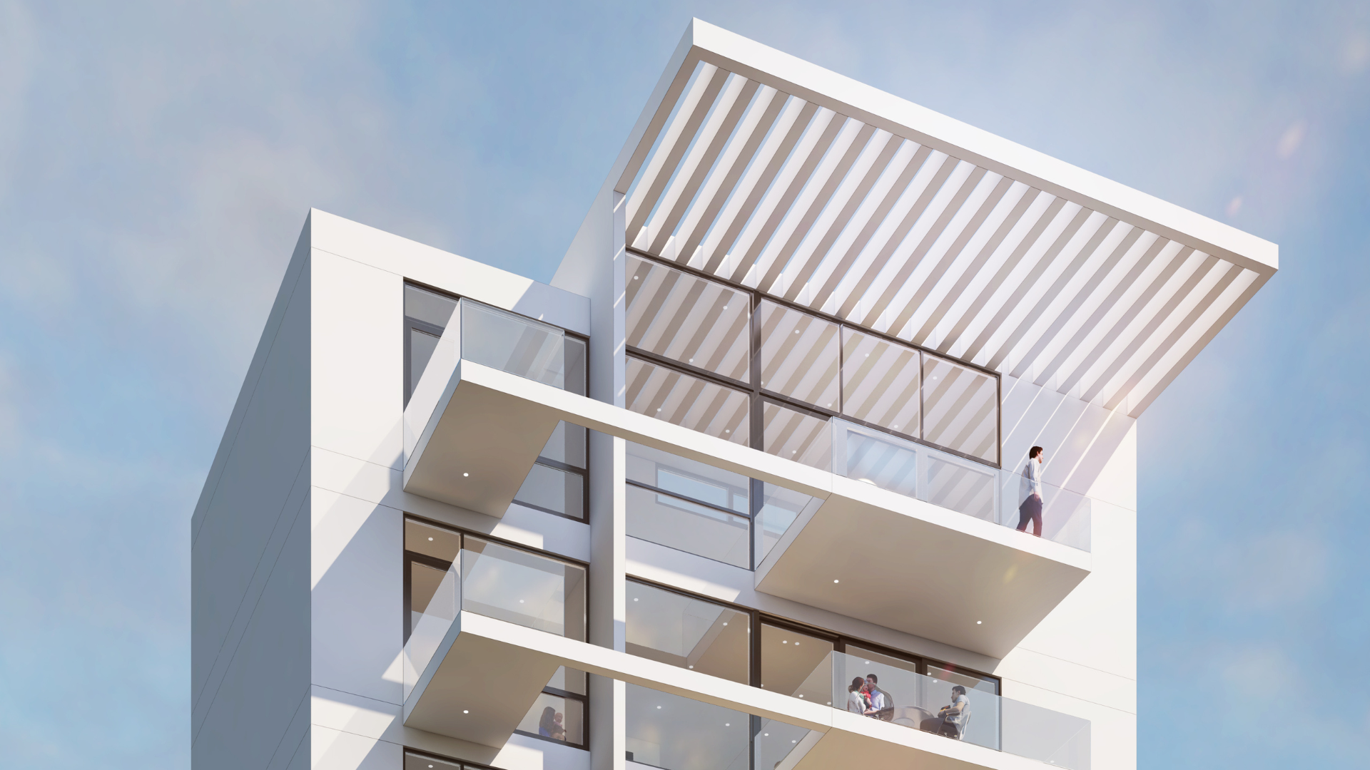 Modern white apartment building with glass balconies and a large pergola-style roof feature, seen from below against a blue sky. A person stands alone on the top balcony.