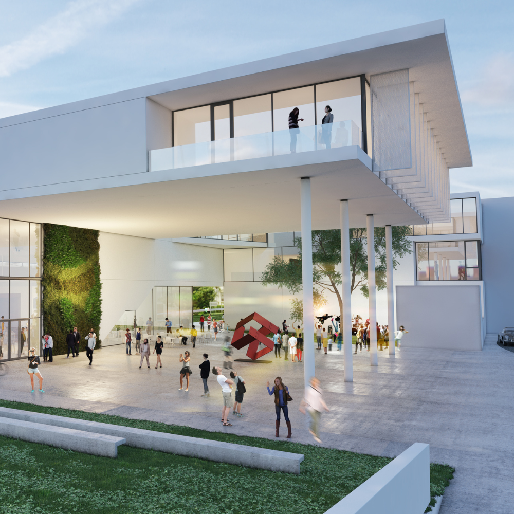 Modern building with large glass windows, featuring a courtyard where people gather. Two individuals stand on a balcony above. Theres a red geometric sculpture in the open area, and greenery is visible at ground level.
