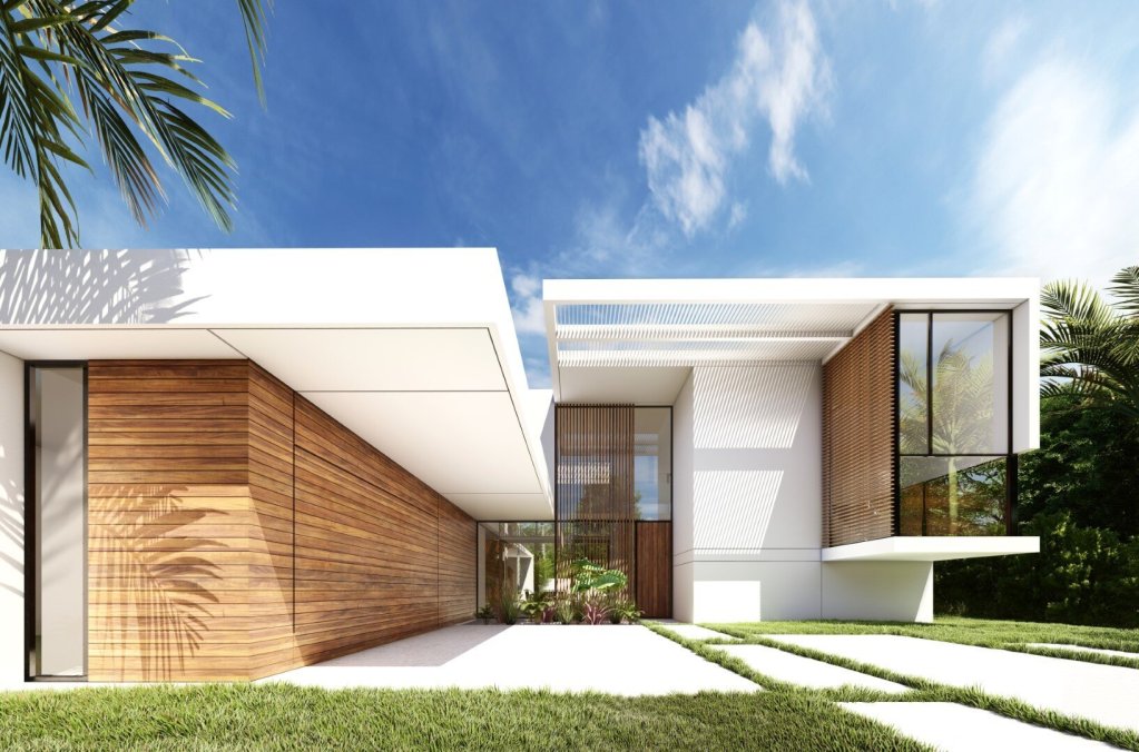 Modern house with clean white lines, large glass windows, and wood paneling, surrounded by green grass, tropical plants, and a blue sky with some clouds.