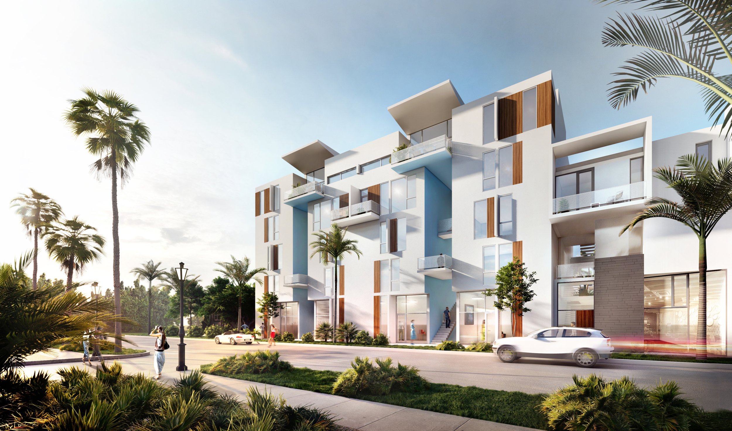 Modern white apartment building with balconies, palm trees, and landscaped greenery under a clear sky; a car drives by and a person walks on the sidewalk in the foreground.