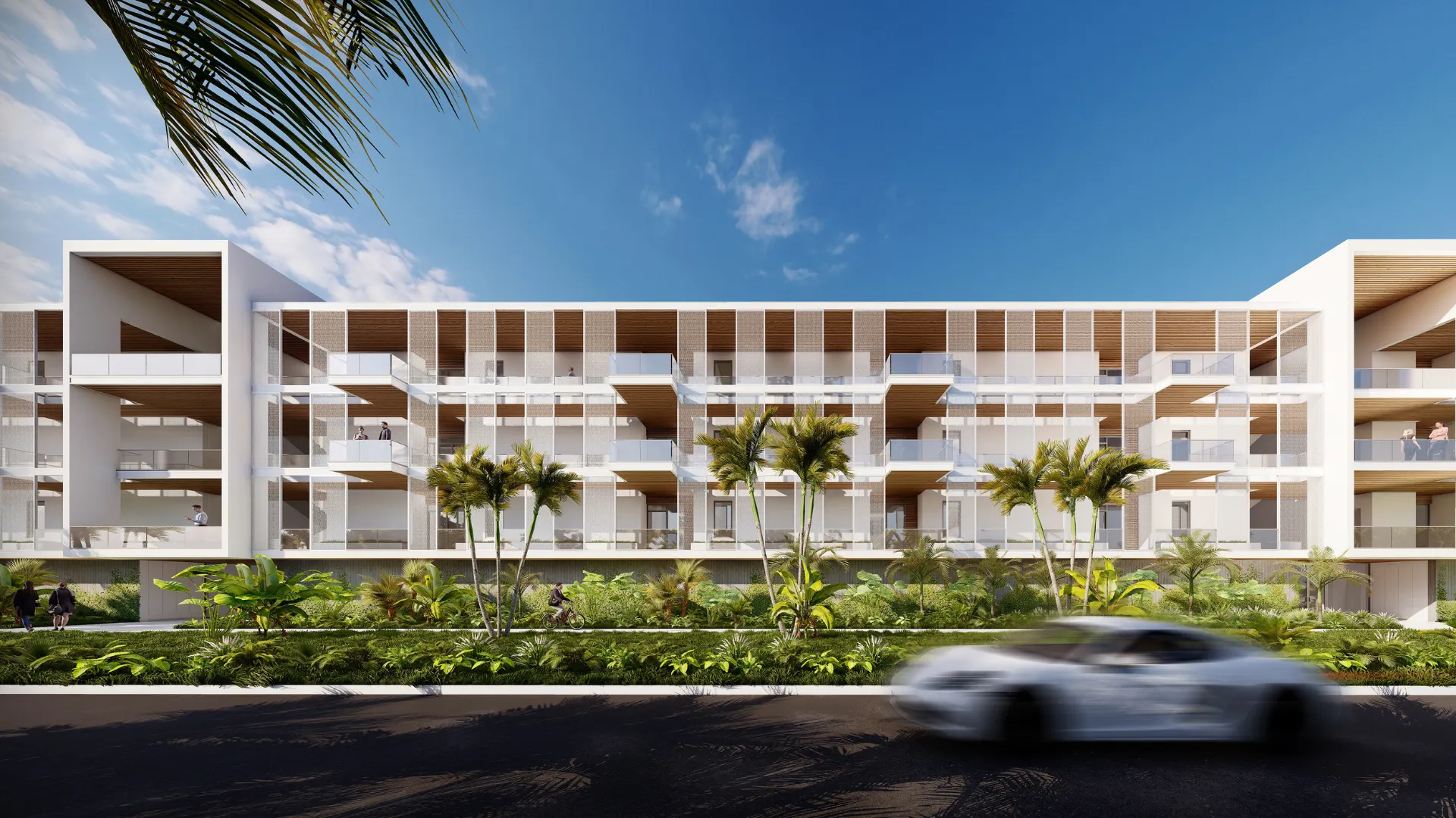 Modern white apartment building with balconies, surrounded by palm trees and lush greenery under a blue sky. An awards-winning design, with a white car driving past on the road in the foreground.