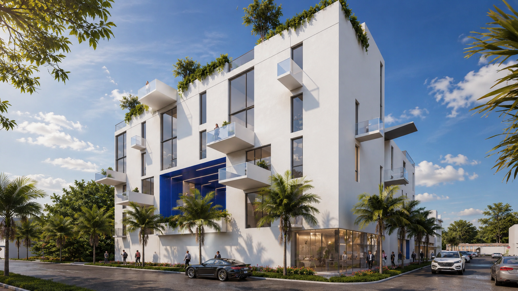 Modern white apartment building with large windows, balconies, rooftop greenery, and palm trees in front. People are walking on the sidewalk, and cars are parked along the street under a blue sky with scattered clouds.
